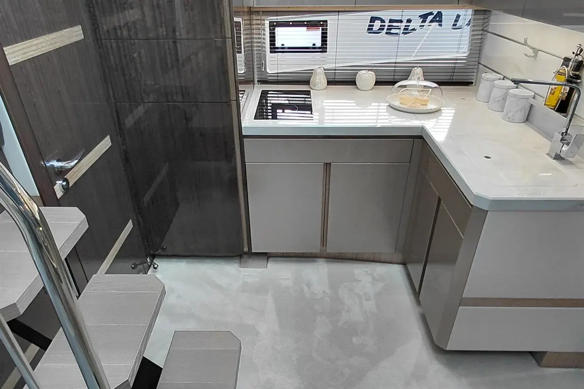 Modern kitchen with sleek cabinetry, glass hob, and marble counter, featuring decorative items and a digital display labeled "DELTA.